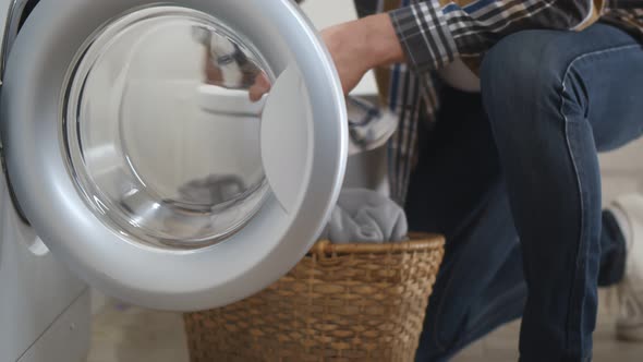 Side View of Senior Man Loading Washing Machine in Bathroom