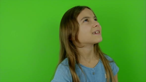 The Child Looks Up and Laughs Against a Green Background