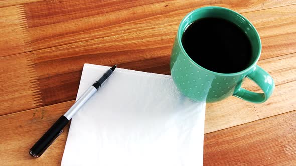 Close-up of coffee mug with blank paper and pen