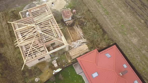 Top down aerial view of two private houses, one under construction with wooden roofing frame 