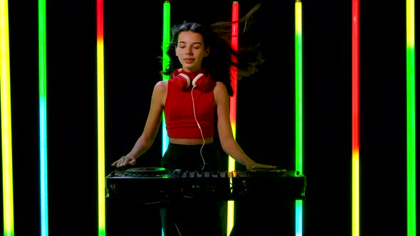 Portrait of a Young Pretty Woman in Big Red Headphones Plays Turntables Electronic Dance Music and