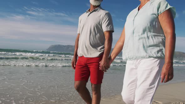 Senior african american couple walking and holding hands at the beach