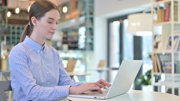 Laptop Use By Young Businesswoman Looking at Camera in Cafe