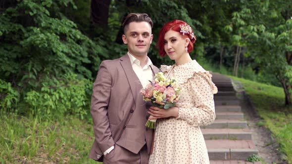 Portrait of a Beautiful Bride and Groom in Forest in Park with Wedding Bouquet of Flowers