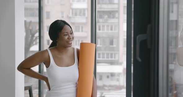 Exhausted Black Woman Holding a Fitness Mat