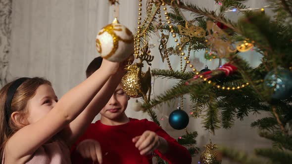 Decorating the Christmas Tree Hanging Ornaments a Girl and Boy Clings a Toy