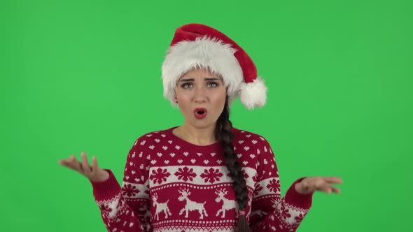 Portrait of Sweety Girl in Santa Claus Hat Is Upset, Waving Her Hands in Indignation, Shrugging