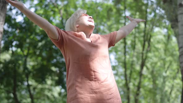 Bottom Angle View of Happy Relaxed Woman in Sunglasses Enjoying Sunny Day in Summer or Spring Park