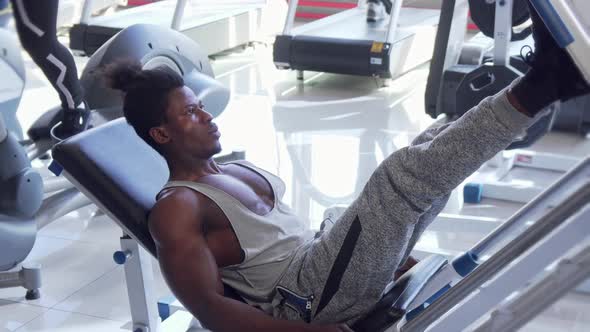 Athletic Young African Man Working Out on Leg Press Machine at the Gym