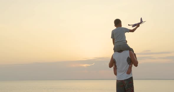 Happy Father and Son Playing with Airplane Toy Together at Sunset Happy Family Walking Outdoors