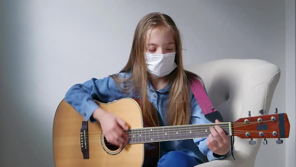 Playing guitar at home in quarantine time. Young girl stay at home alone