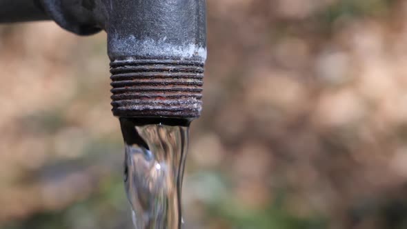 Close up shot of a rusty fountain with crystal clear water in slow motion.