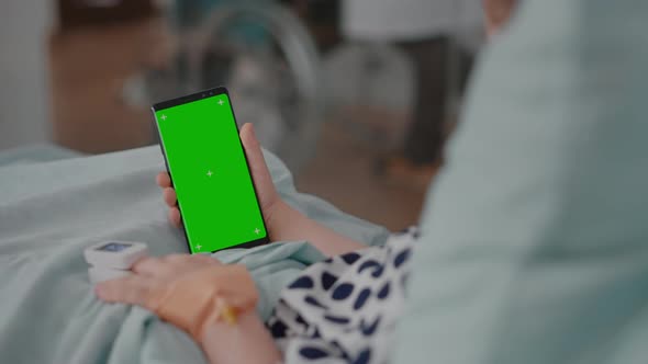 Sick Girl Holding Mock Up Green Screen Chroma Key Phone with Isolated Display During Recovery
