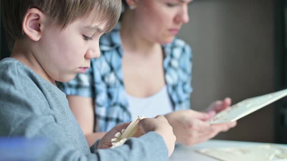 boy and his mother are enthusiastically making wooden toys at the table