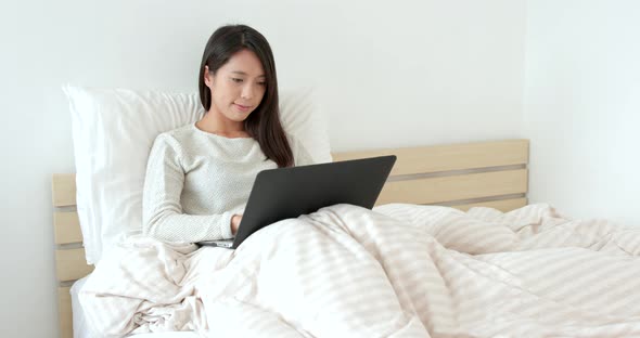 Woman working laptop computer on bed