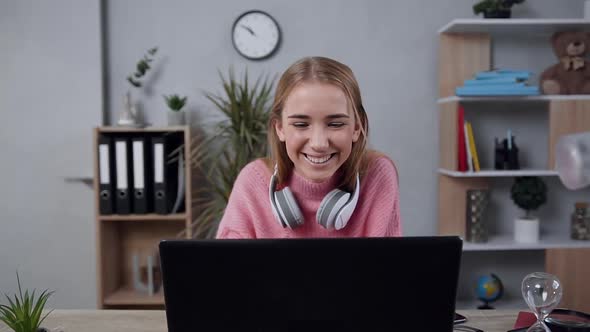 Young Blond Girl in Pink Sweater which Looking at Monitor and Sincerely Smiling