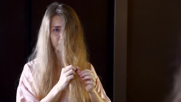 Unhappy Woman with Dry Brittle Hair Checking Her Tangled Hair in Mirror