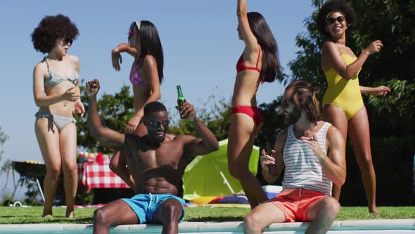 Group of diverse friends dancing and enjoying near the pool