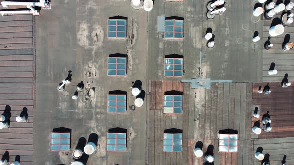 Flying over the roof of an old factory with a plank roof and ventilation pipes.