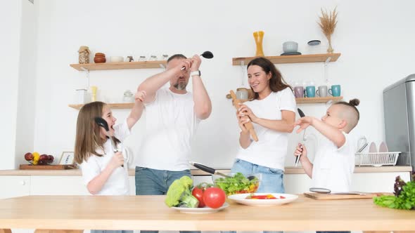 Funny Young Couple Singing and Dancing in the Kitchen Using Spoons Instead of a Microphone