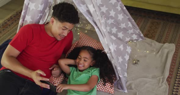 Happy biracial father and daughter using smartphone together