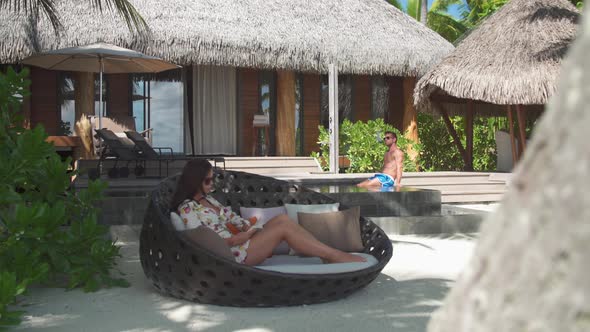 A man and woman couple relaxing and reading a book in the tropical islands in French Polynesia.