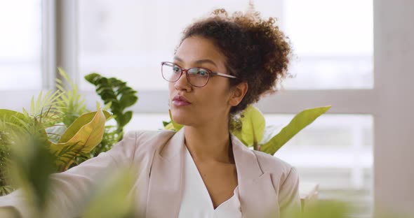 Businesswoman sitting among plants drinking coffee