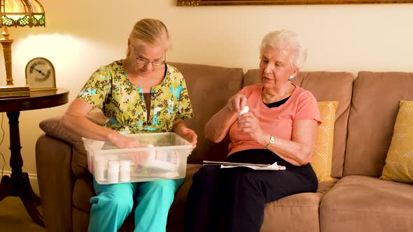 Home healthcare nurse and elderly woman review medications and try opening lids.