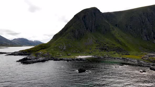 Drone flying towards mountain island with a pack of birds flying by.