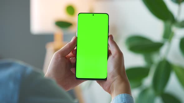 Woman at Home Using Smartphone with Green Mockup Screen in Vertical Mode