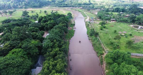 Aerial shot of Elephants standing in the river with fields on each side.