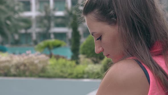 Tourist with Ponytail Stands Against Blurred Resort Hotel