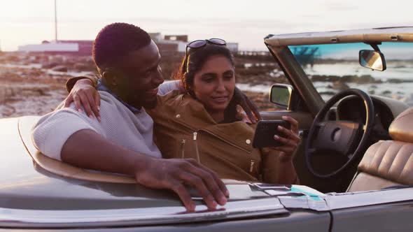 African american couple taking a selfie while sitting in the convertible car on the road