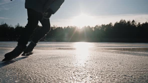 Man Practice Ice Skating Tricks on a Clear Frozen Lake on a Sunny Winter Day