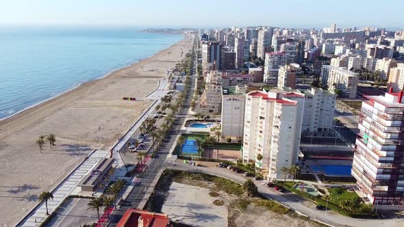 Aerial drone footage of high buildings with swimming pools near the sea and beach of San Juan, Spain