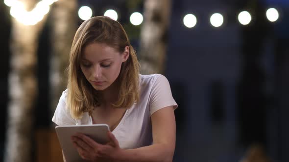 Teenage Girl Using a Tablet Sitting in Outdoor Cafe.