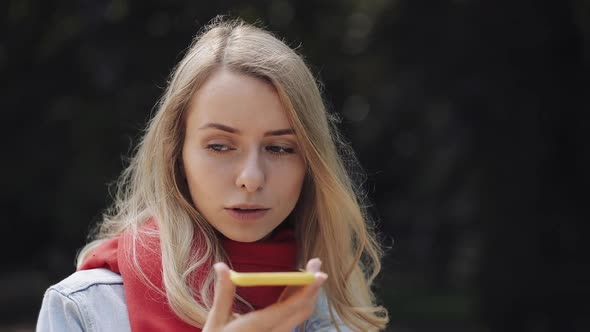 Younf Beautiful Woman Wearing Red Scarf Sending Audio Voice Message on Cellphone at Outdoor Talking