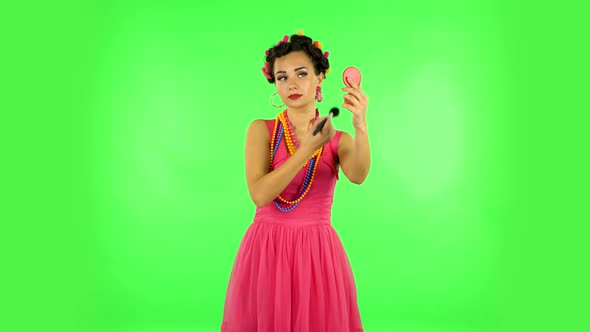 Girl with Curlers on Her Head in a Pink Dress Looking in Red Mirror and Powdered Her Nose