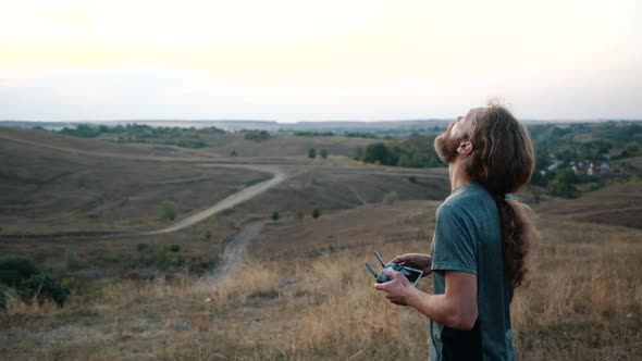 Man Operating a Drone with Remote Control. Slow Motion. Drone Pilot Looks Up While Touching the