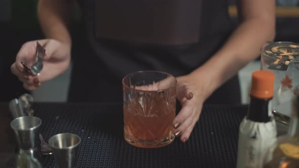 Mixologist adds cherry garnish to whiskey craft cocktail in rocks glass.
