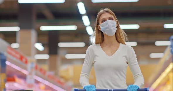 Young Woman in a Medical Mask Walks Through the Store Shopping in the Supermarket