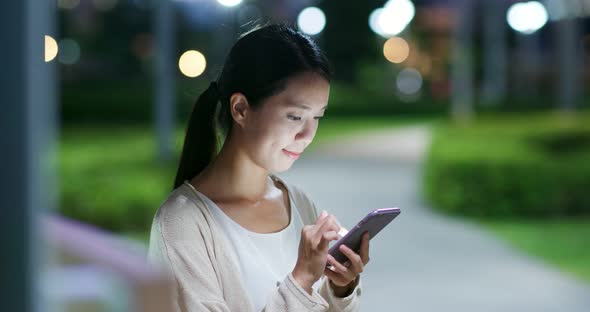 Woman work on mobile phone in city at night