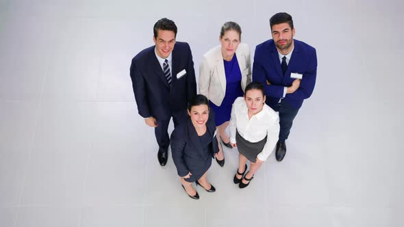 Smiling businesspeople showing thumbs up and peace hand sign in office