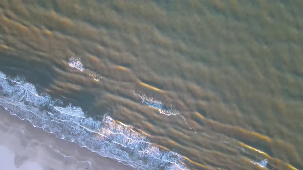 Aerial view of rolling waves and sunrise at the ocean close to Løkken by the North Sea, Denmark