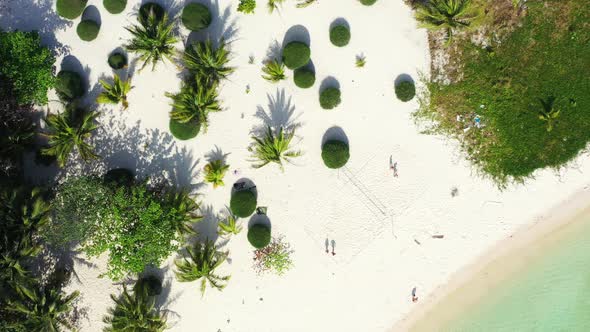 Tourists playing volleyball on the paradise white sand beach with exotic trees and round bushes. Mal