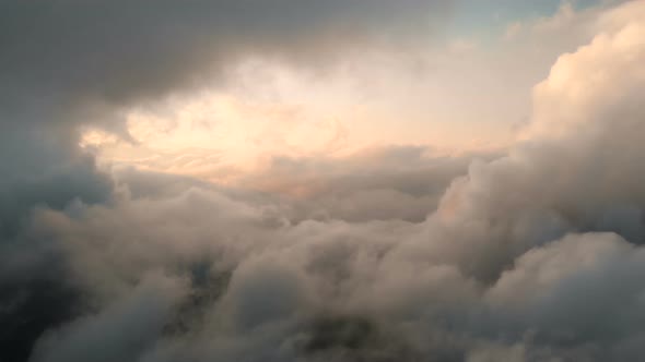 Aerial View Flying Through Cumulus Thunderclouds at Sunset. Gold Colored Sunset Cloudiness