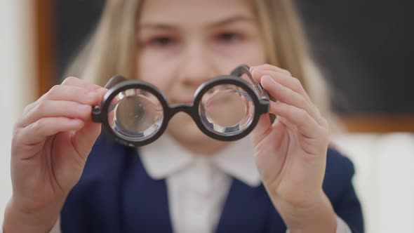 Closeup High Dioptres Glasses in Hands of Blurred Teenage Schoolgirl