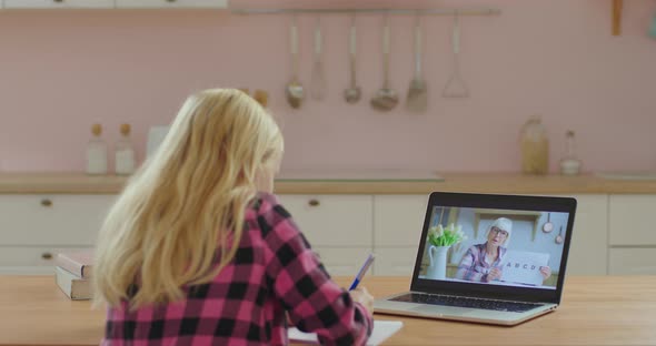 School Child Studying Online with Senior Female Teacher on Laptop Screen. Little Girl Has Online