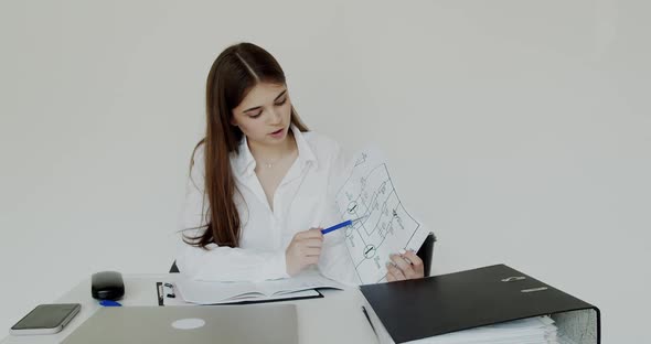 Young Girl Talking and Explaining the Printouts at Camera During Remote Working