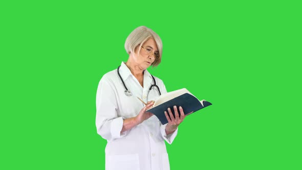 Mature Woman Doctor with a Stethoscope Reading Log on a Green Screen Chroma Key